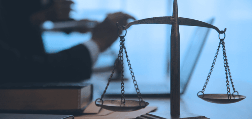 Scales of justice on a desk with legal books, symbolizing analysis of UAE tax laws by the former Chief Justice