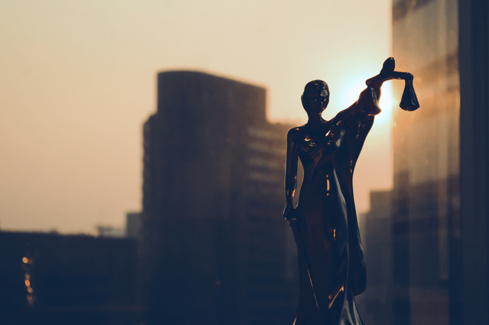 Statuette of Lady Justice against a city skyline, representing the legal principle of divisibility in an arbitration award as established by the Court of Cassation.