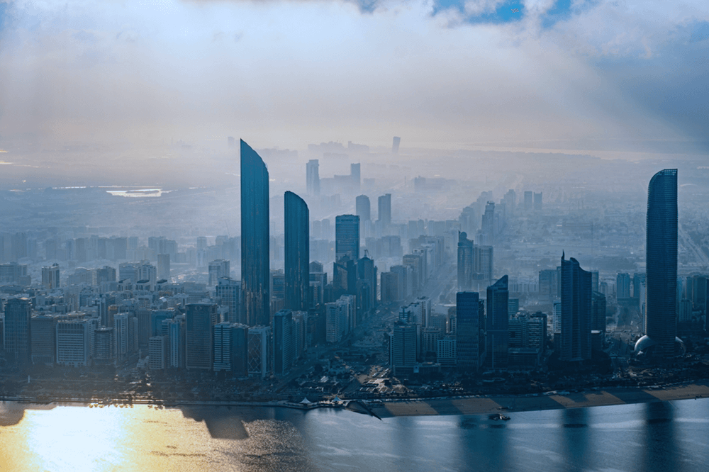 Aerial view of Abu Dhabi skyline with modern skyscrapers and coastal landscape, highlighting urban development and environmental progress
