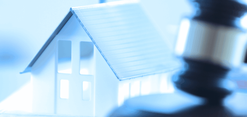 Miniature house model with judge's gavel representing real estate register law and property legislation enforcement