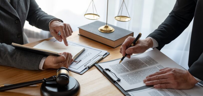 Two legal professionals reviewing and signing a contract with a judge’s gavel and scales of justice on the desk, symbolizing precautionary attachment procedures in UAE civil law.