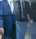 Law firm professionals in suits walking through a hallway, symbolizing brokers who bring clients to law offices