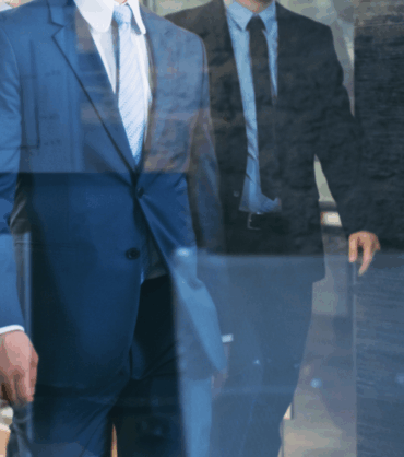 Law firm professionals in suits walking through a hallway, symbolizing brokers who bring clients to law offices