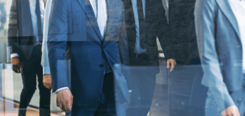 Law firm professionals in suits walking through a hallway, symbolizing brokers who bring clients to law offices