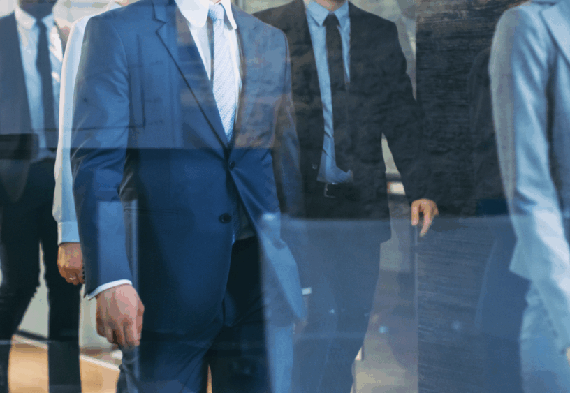 Law firm professionals in suits walking through a hallway, symbolizing brokers who bring clients to law offices